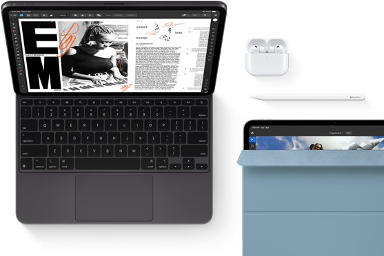 iPad Pro attached to Magic Keyboard, front exterior, space black colour, rounded corners, black display bezel, open, display showing article editing app with text and photograph of a woman playing music, Airpods 4 in open case, blue Smart Folio cover on iPad Pro with Apple Pencil Pro resting atop device, cover slightly open revealing display