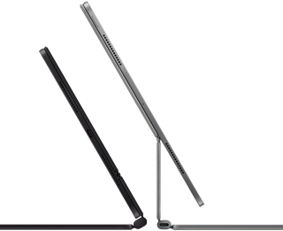 Two iPad Pro devices attached to Magic Keyboard, side exterior, thin profile, space black colour with speakers and USB-C port, tilted half open, silver colour, open, tilted back showing the keyboard’s floating cantilever design, speakers and microphone